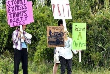 Stormy supporters hold signs across from a “Gentlemen’s Club” in Salisbury