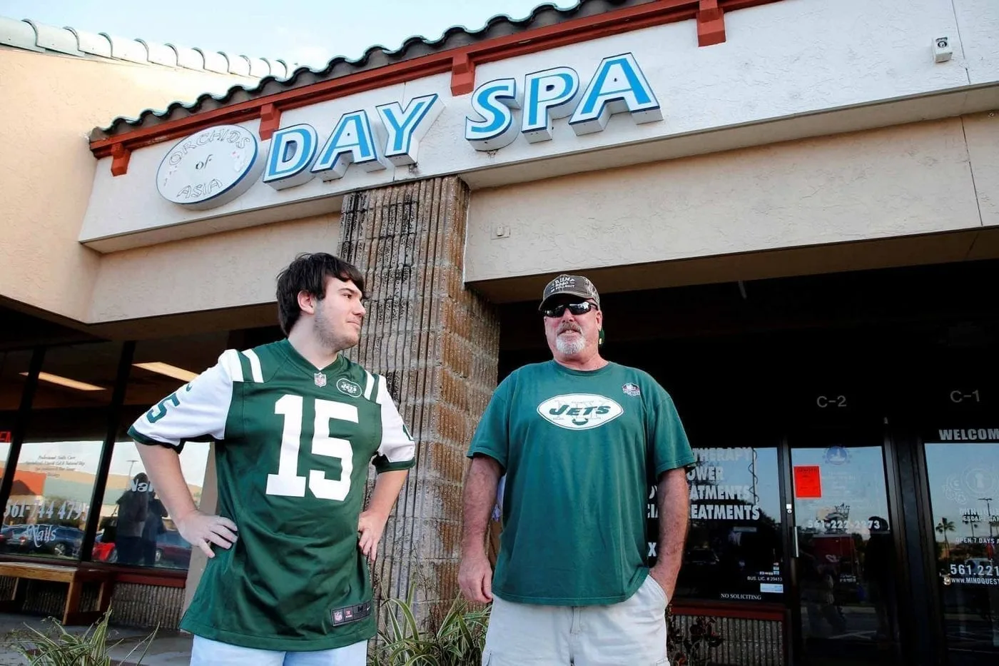 New York Jets fans Kevin Brown (R) and Matthew Gizze of Jupiter stand in front of Orchids of Asia Day Spa & Massage in Jupiter,